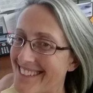 A woman with glasses smiling for the camera.