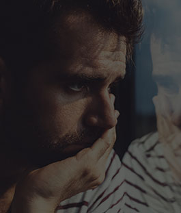 A man with his hand on his face looking out of the window.